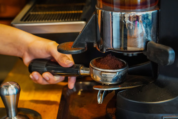 Focus Selection : The barista's hand is holding a filter and pressing the coffee to make an espresso