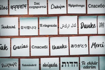 Notes with the word "Thank you" in various languages of the world on a wooden background