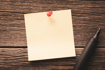 Close up of empty blank note paper pinned to a wooden background and black marker
