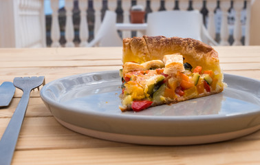 Presentation of a slice of healthy vegan pie made of vegetables and baked. Wellness and diet. Wooden table.