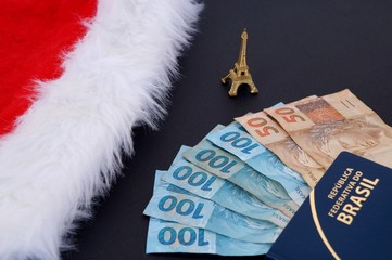 Santa Claus hat, little Eiffel Tower, Brazilian money and Brazilian passport. Travel to France at Christmas concept. 