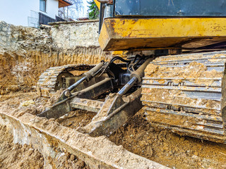 Yellow bulldozer excavator shoveling and digging the ground while working on the difficult excavation, new modern industrial machinery for heavy work