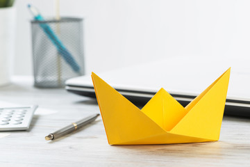 Businessman desk with yellow paper ship