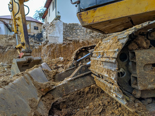 Fototapeta premium Closeup of yellow digger, bulldozer or excavator working on the site excavation, digging up the ground for new modern construction to take place