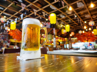 Wide closeup detail of a stein glass of beer on a tabletop at a Japanese Izakaya restaurant. Bangkok, Thailand. Travel and drinks.