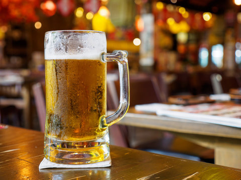 Closeup macro detail of a stein glass of beer on a tabletop at a Japanese Izakaya restaurant. Bangkok, Thailand. Travel and drinks.