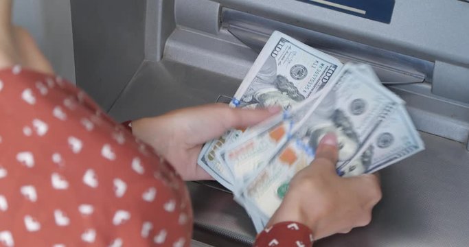 Woman counting money near cash machine outdoors, closeup