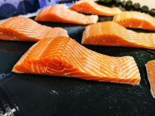 Closeup: Fresh raw salmon fillet on black background. Uncooked fish for sale in supermarket