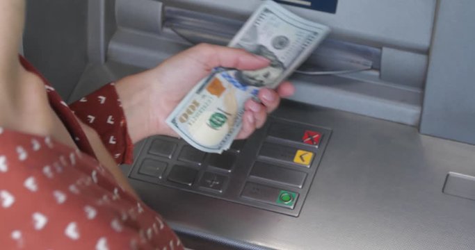 Woman counting money near cash machine outdoors, closeup