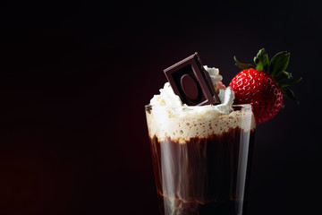Coffee drink with whipped cream, strawberry and pieces of black chocolate.