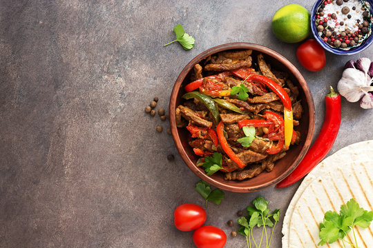 Mexican Food Fajitas And Salsa Sauce On A Dark Rustic Background. Traditional Mexican Dish. View From Above, Flat Lay, Copy Space.