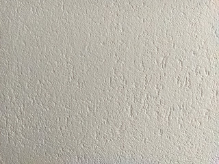 Grunge looking rough white wall inside the house with a lot of texture to it. Interior surface of the wall.