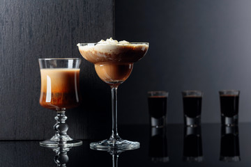 Coffee cocktails and liquor on black reflective background.