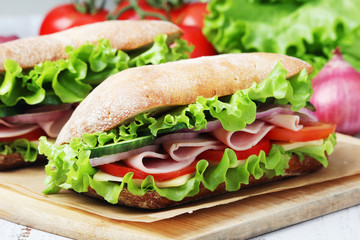 Two sandwiches with fresh vegetables, ham and cheese in ciabatta bread	