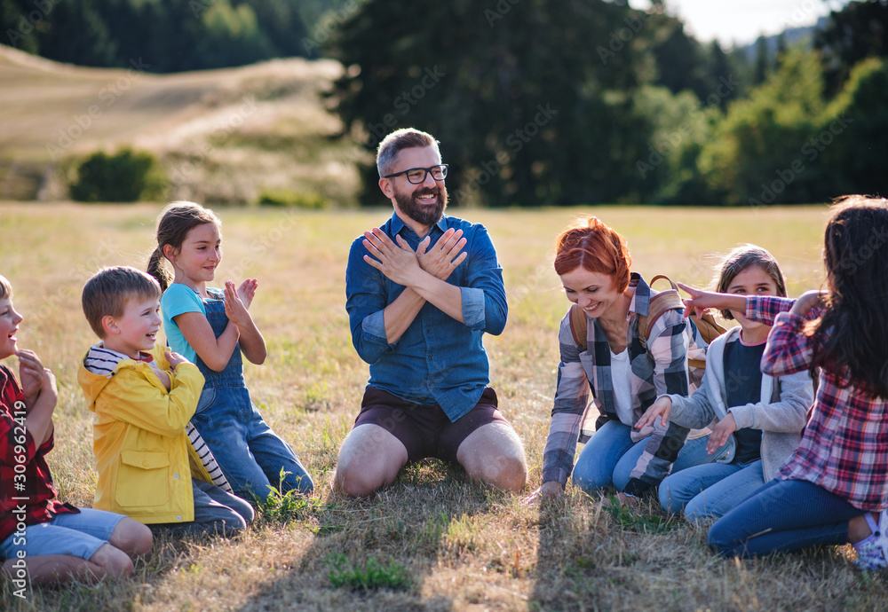 Sticker Group of school children with teacher on field trip in nature, chanting.