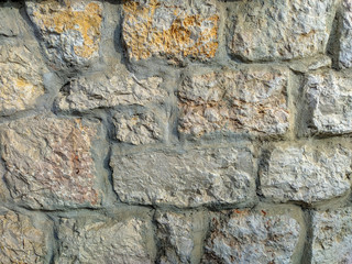 Old and retro looking wall made of stone rock bricks on an outside wall, very rugged and weathered structure