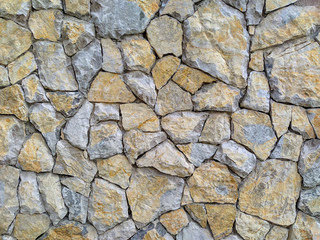 Cool and modern colorful stone rock bricks stacked into a wall facade for natural look and interesting wallpaper background