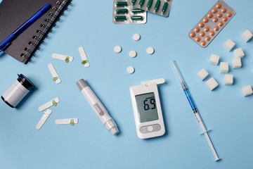 Medicine, healthcare, technology and online pharmacy concept. A diabetic measures your blood glucose. Top down view of pills, glucometer, syringe. World Diabetes Day, November 14th.