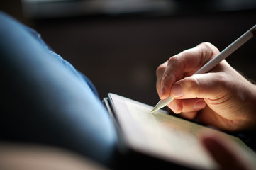 Hand schreibt mit einem Eingabestift auf einem Tablet
