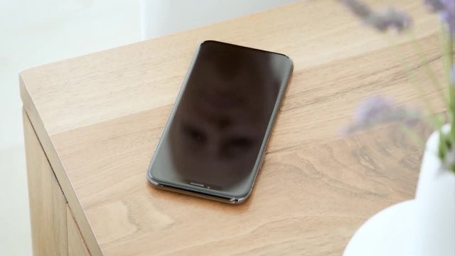 hand Take a smart mobile phone from a wooden table, close up