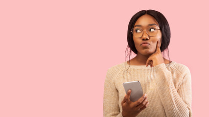 Black Woman Holding Mobile Phone Thinking Standing In Studio, Panorama