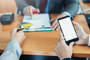 Fototapeta premium Businessman holding a smartphone with a white screen. Bank staff Stamping and approve credit cards.