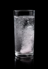 Soluble pill tablet in water with bubbles on black