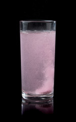 Soluble pill tablet in water with bubbles on black