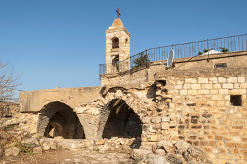Fototapeta na wymiar back of the ancient stone maronite church in baraam national park in israel showing two arches and the bell tower with a clear blue sky background