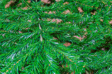 Assembled artificial green Christmas tree detail inside house. Green fake branches shaping a festive pine tree, without ornaments.