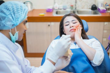 Asian dentist and the patient are preparing to treat carious teeth in the dental clinic