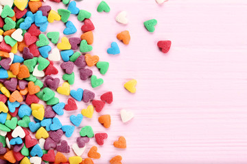 Colorful heart shaped sprinkles on pink wooden table