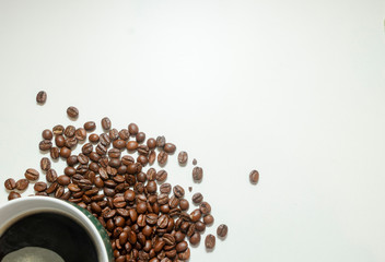 The cup of black coffee with coffee beans with wooden spoon. White background.