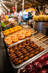 Grill and fried silkworm pupae in a food market in Beijing, China.