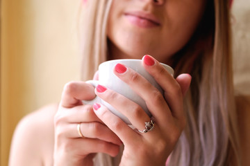 sexy girl sitting at the table and drinking coffee. single woman in white men's shirt
