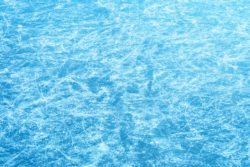 Winter ice rink. Traces of blades of skates on ice, blue winter background