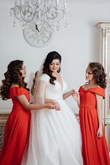 Happy girls at their best friend's wedding. Beautiful and elegant bride with bridesmaids. Gorgeous bride with her girlfriends posing in the room. Morning of beautiful bride