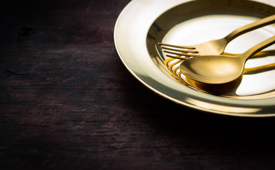 Brass Spoon, fork and plate on wood table