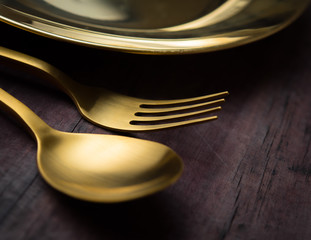 Brass Spoon, fork and plate on wood table