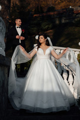 Bride and groom posing on the stairs. Just married loving couple in wedding dress and suit in autumn. Bride and groom having a romantic moments on their wedding day.
