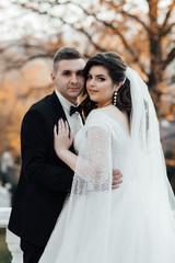 Obraz premium Stylish and beautiful. Newlyweds in a autumn park outdoors. The groom in a black suit. Happy and young married couple. Autumn wedding