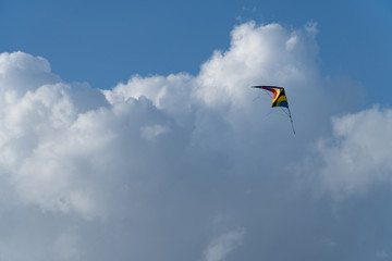 A colorful kite flying in the air, the blue sky in the background
