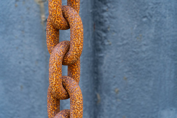 A thick rusty orange chain in front of blue background - security concept