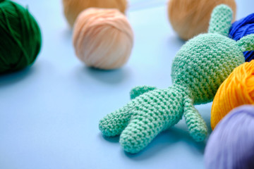 Naklejka premium Bright color yarn clews with pastel green stuffed bunny on the blue background. Concept of amigurumi toy making, handcrafting, knitting, hobbie