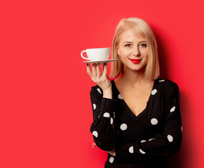 beautiful french woman holds cup of coffee on red background