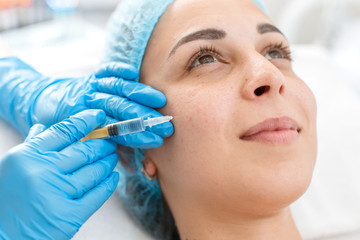 Close-up, beautician makes beauty injections into the skin of a young beautiful girl. Facial care...