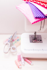 white professional sewing machine on the table, fabrics for girls, scissors and spools of thread, front view, copy space,white background