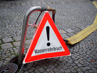 Wasserrohrbruch - Warnschild sichert den Gefahrenbereich ab	