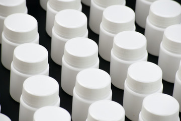 Several white medicine containers in a row on black background