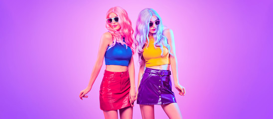 Two sexy adorable Fashion woman in party outfit dance, Trendy neon light hairstyle. Night club...